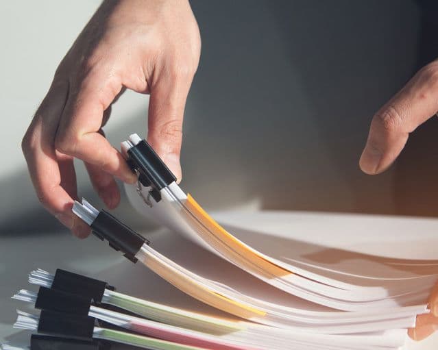 Hands picking up several documents from a desk